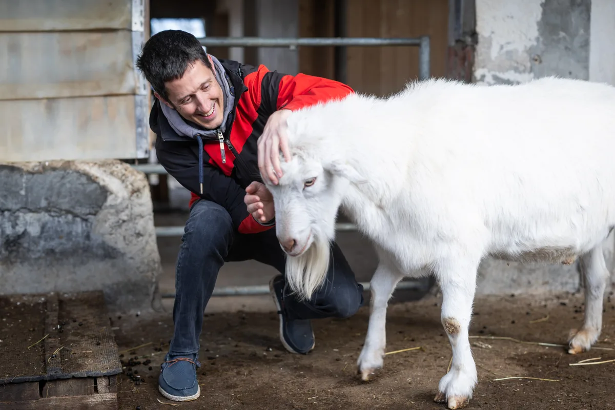 Georg Klingler lacht und streichelt einen Ziegenbock.